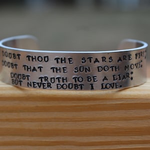 May include: A silver metal bracelet with the inscription "Doubt thou the stars are fire, Doubt that the sun doth move, Doubt truth to be a liar, But never doubt I love."