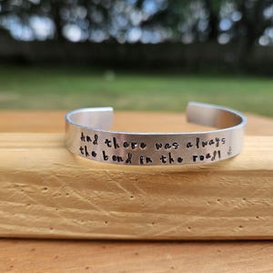 May include: Silver bracelet with the inscription "And there was always the bend in the road".