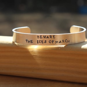 May include: Silver metal bracelet with the inscription "Beware the Ides of March".