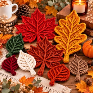 May include: A collection of crocheted leaves in various shapes and colours, including red, orange, yellow, green, cream, and brown. Each leaf features detailed, raised stitching that mimics natural veins, creating a textured, handcrafted appearance.
