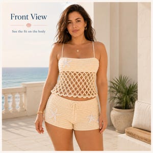 Peut inclure: Un ensemble deux pièces en crochet couleur crème composé d'un haut à fines bretelles et d'un short. Le haut présente un corsage uni et une section centrale en maille ajourée circulaire. Les deux pièces sont ornées d'étoiles de mer blanches.