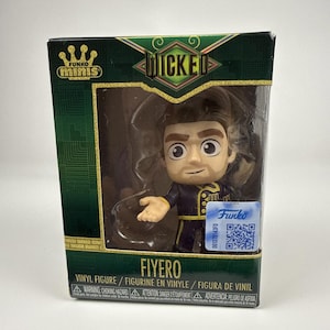 May include: A Funko Minis vinyl figure of Fiyero from Wicked, encased in a green and gold display box. The figure has brown hair, a light complexion, and wears a dark blue uniform with gold trim. The box features the Wicked logo and text.