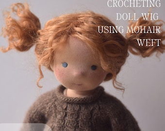 Op de afbeelding: Een handgemaakte pop met rood haar in staartjes. De pop heeft blauwe ogen en sproeten. Ze draagt een bruine trui. Tekst op de afbeelding luidt "VIDEO TUTORIAL CROCHETING DOLL WIG USING MOHAIR WEFT" en "VIDEO".