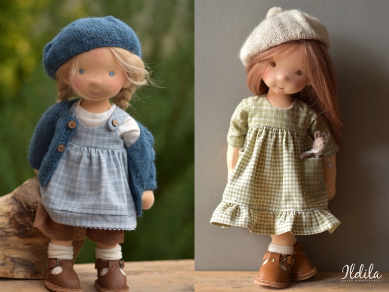 May include: Two handmade cloth dolls wearing dresses and hats. The doll on the left is wearing a blue and white plaid dress, a blue cardigan, and a blue beret. The doll on the right is wearing a green and white plaid dress, a beige beret, and is holding a small stuffed mouse.