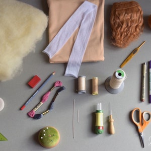 May include: A collection of craft supplies for making a doll, including yarn, fabric, felt, needles, thread, and a crochet hook.