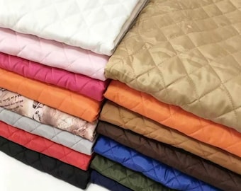 以下が含まれることがあります： 白、ピンク、マゼンタ、オレンジ、ベージュ、茶色、青、緑、黒などの様々な無地のキルティング生地を折り畳んで積み重ねたもの。その中には、文字やイラストがプリントされた柄の生地が1枚含まれている。