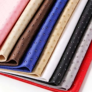 May include: A collection of folded fabric sheets in various colors including pink, beige, brown, blue, white, black, gray, and red. Each piece of fabric features a uniform pattern of small, raised, circular silicone dots across the surface.
