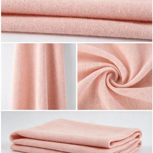 May include: A soft, light pink fabric with a visible woven texture. The textile is displayed in multiple views, including folded layers, a draped vertical section, and a circular swirl, showcasing the consistent pastel color and weave pattern.