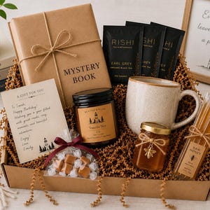 May include: A gift box containing a brown paper-wrapped mystery book, three Rishi Earl Grey tea sachets, a speckled ceramic mug, a jar of Vanilla Sky soy candle, a small jar of honey with a bee charm, honey sticks, and a bag of caramel candies.