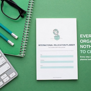 以下が含まれることがあります： 地球儀と箱のアイコンが描かれた白いInternational Relocation Plannerメモ帳。日付、目的地、名前の記入欄があります。テキストは「EVERYTHING ORGANIZED. NOTHING LEFT TO CHANCE. Every step of your move abroad, planned before it happens.」と記載されています。