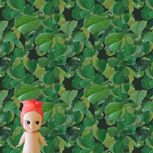 May include: A small, red-haired doll with a pink dress stands in front of a green leafy background. The doll has a sweet, innocent expression.