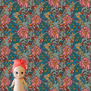 Puede incluir: Una muñeca con el pelo rosa sobre un fondo azul claro con un patrón floral. Las flores son rosas, azules y amarillas.
