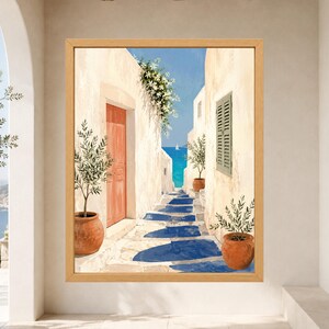 May include: A framed wall art print depicting a Mediterranean alleyway with white stucco walls, a bright orange door, and green potted plants. The stone path leads toward a deep blue sea under a clear sky, featuring long blue shadows and white flowers.