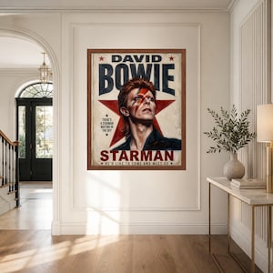 May include: A framed rectangular poster featuring a portrait of David Bowie with a red lightning bolt across his face. The background includes a large red star and the text DAVID BOWIE STARMAN, THERE'S A STARMAN WAITING IN THE SKY, HE'D LIKE TO COME AND MEET US.