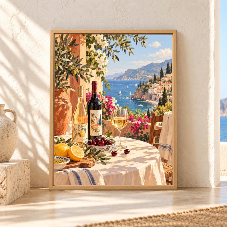 Framed Mediterranean wine wall art showing wine bottles, a glass of white wine, lemons, cherries and olive branches on a sunny terrace overlooking a blue coastal village and sailboats.