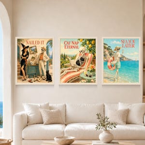 May include: Three framed wall art prints featuring skeleton illustrations. The left print shows a witch and a skeleton with the text NAILED IT. The center print shows a skeleton lounging with the text CAT NAP ETERNAL. The right print shows a skeleton at the beach with the text SEA YOU LATER.