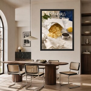 May include: A framed wall art print titled Caviar & Potato Chips featuring a silver bag of golden potato chips, a small metal tin of black caviar, a crystal glass, a lemon, and a white napkin on a table, displayed in a dining room setting.