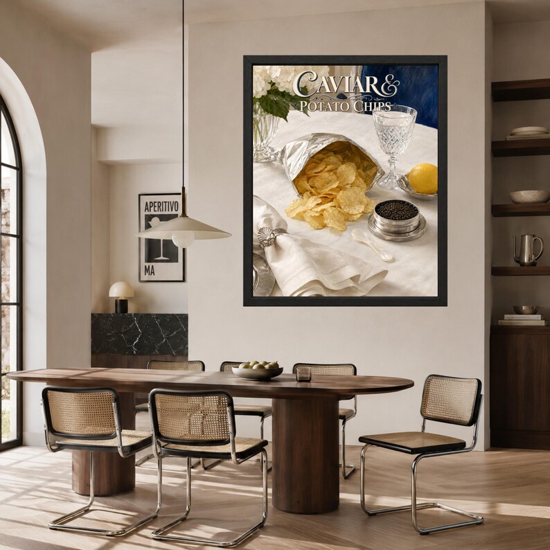 May include: A framed wall art print titled Caviar & Potato Chips featuring a silver bag of golden potato chips, a small metal tin of black caviar, a crystal glass, a lemon, and a white napkin on a table, displayed in a dining room setting.