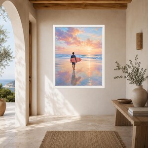 May include: A framed wall art print depicting a surfer walking along a wet sandy beach at sunset, carrying a pink surfboard. The sky is filled with soft pink and orange clouds, and the scene reflects clearly on the water-covered sand surface.