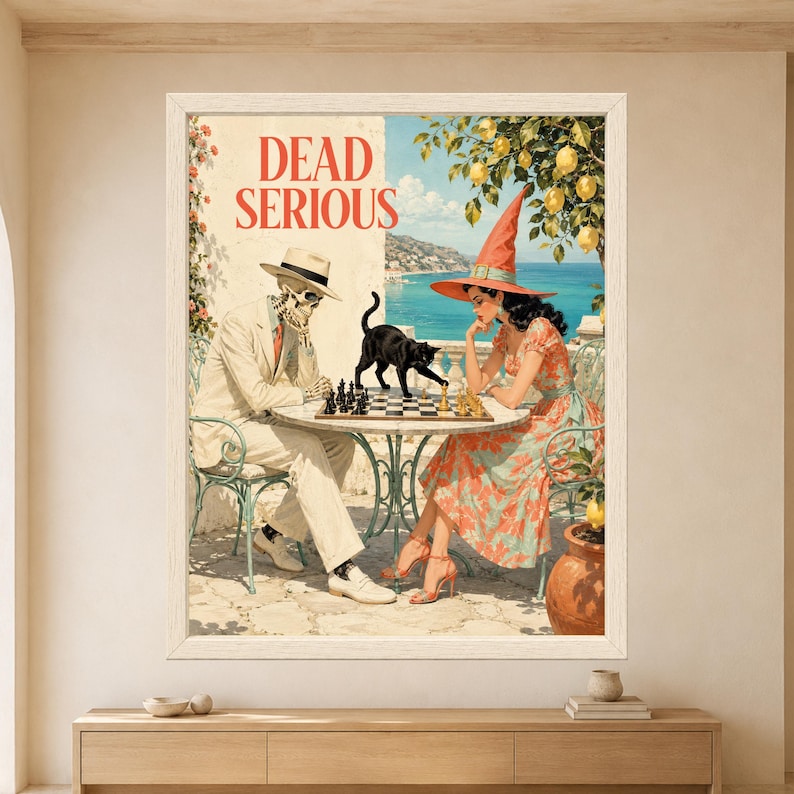 Framed Dead Serious wall art showing a skeleton and retro witch playing chess at a sunny seaside café while a black cat walks across the chessboard beneath a lemon tree.
