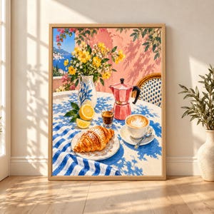 Framed Mediterranean breakfast wall art showing a pink moka pot, cappuccino, espresso, croissant and fresh lemons on a blue-and-white table beside yellow flowers and a sunny coastal view.