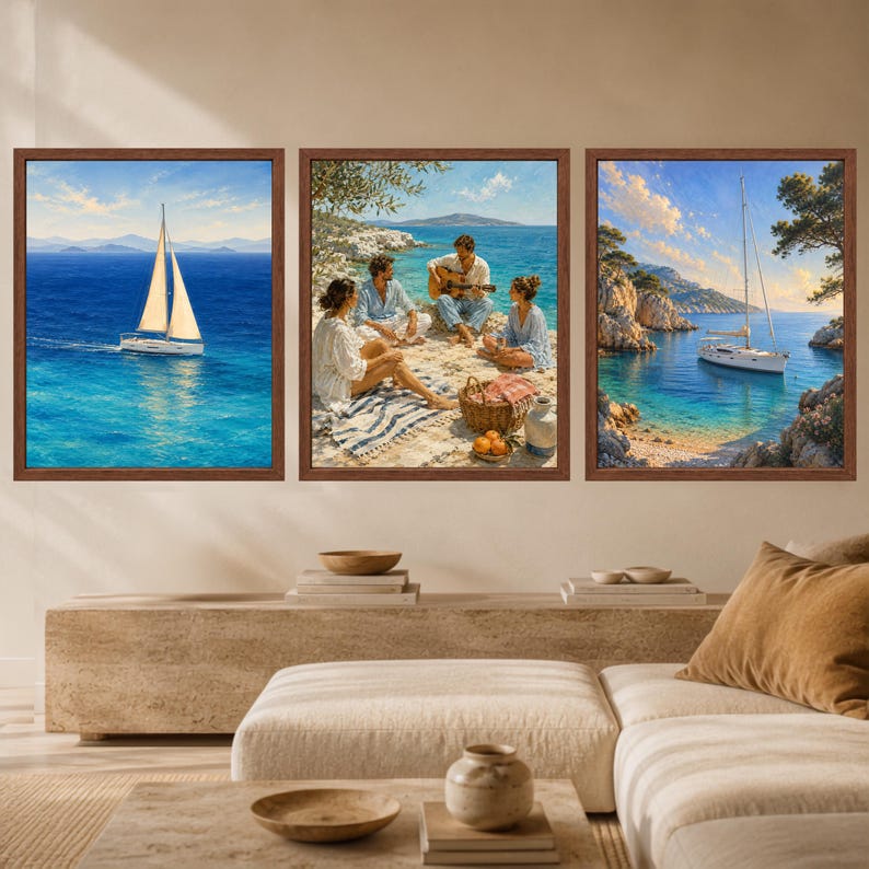 May include: A set of three framed wall art prints featuring coastal scenes. The left print shows a sailboat on blue water, the center depicts three people sitting on a rocky shore with a guitar, and the right shows a sailboat in a cove.
