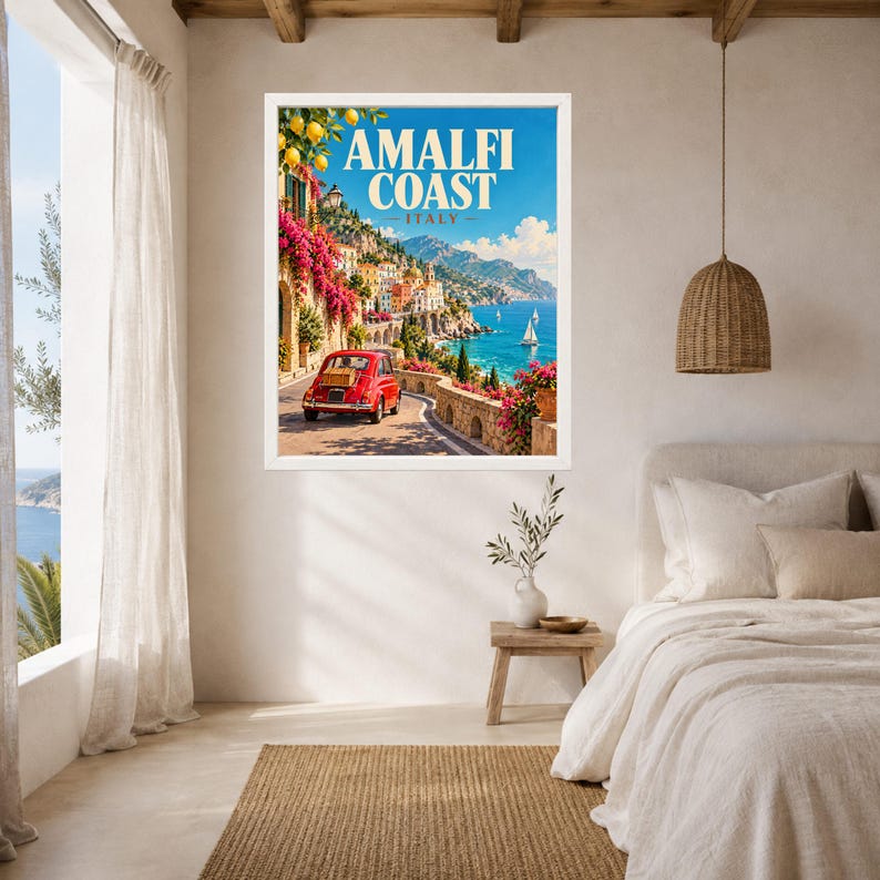 May include: A framed wall art print featuring a vibrant travel poster of the Amalfi Coast, Italy. The illustration depicts a red vintage car on a coastal road, bright pink bougainvillea, yellow lemons, and blue sea with sailboats under a clear sky.