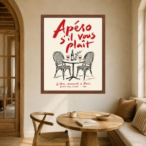 May include: A framed wall art print featuring a cream background with red handwritten text that reads Ap&eacute;ro s'il vous pla&icirc;t. Below the text is a black ink illustration of a bistro table with two chairs, a wine bottle, and two glasses.
