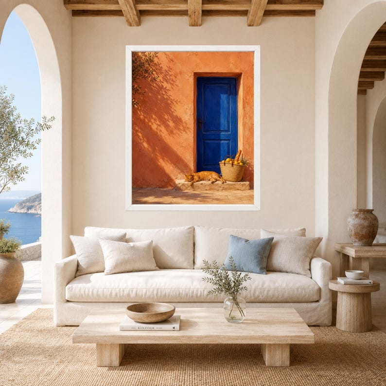 Pu&ograve; includere: Una stampa d'arte da parete incorniciata che raffigura una parete in stucco arancione vibrante con una porta in legno blu intenso. Un gatto arancione riposa sul gradino in pietra accanto a un cesto di vimini pieno di limoni gialli.