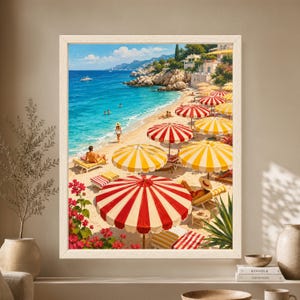 Framed Mediterranean beach wall art showing red and yellow striped umbrellas along a turquoise Riviera coastline with swimmers, sunbathers, rocky cliffs and bright white seaside villas.