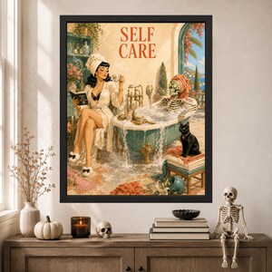 May include: A framed wall art print titled SELF CARE featuring a person in a white robe and towel reading a book while a skeleton in a towel relaxes in a clawfoot bathtub filled with bubbles. A black cat sits on a stack of towels nearby.