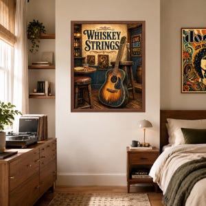 Op de afbeelding: Een ingelijste kunstdruk getiteld Whiskey Strings met een akoestische gitaar die tegen een houten kruk leunt in een schemerige bar, met een glas whisky op een tafel en blauwe muren, tentoongesteld in een slaapkamer met een bed en dressoir.