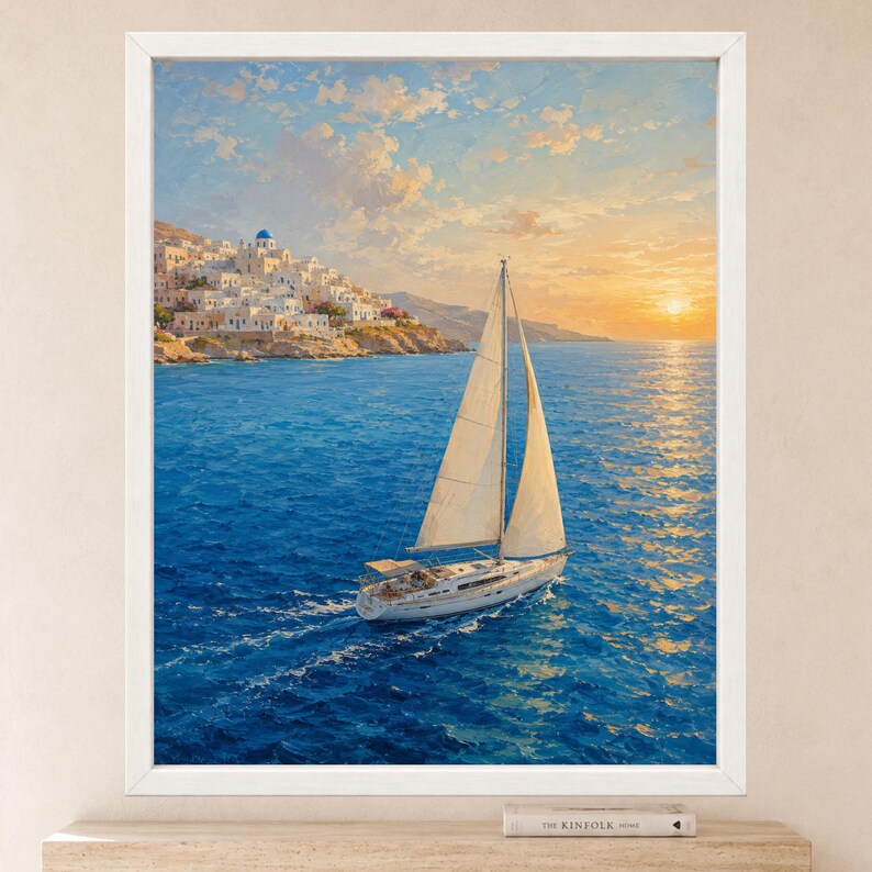 May include: A framed wall art print depicting a white sailboat on deep blue water with a coastal village featuring white buildings and a blue dome in the background under a golden sunset sky with soft clouds, all encased in a simple white frame.