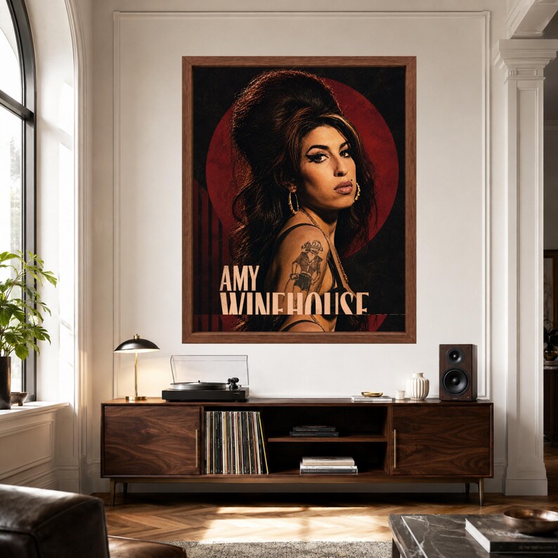 Puede incluir: Una impresi&oacute;n art&iacute;stica enmarcada que presenta un retrato de Amy Winehouse con su caracter&iacute;stico peinado de colmena, delineador de ojos oscuro y pendientes de aro. El fondo es un c&iacute;rculo rojo intenso sobre negro, con el texto AMY WINEHOUSE en beige.