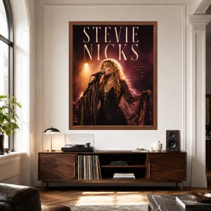 May include: A framed wall poster featuring a photograph of Stevie Nicks performing on stage with a microphone, wearing a dark dress with long fringe sleeves. The text STEVIE NICKS appears in large letters above, with the words LIVE IN THE MOMENT MAGIC IS REAL.