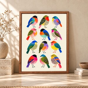 Framed colorful bird wall art featuring twelve hand-painted folk art birds in blue, pink, orange, yellow and green arranged on a warm cream background.