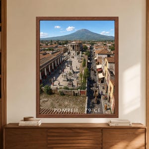 Framed Pompeii 79 CE wall art showing a busy ancient Roman city with a columned temple, stone streets, terracotta rooftops and Mount Vesuvius rising under a clear blue sky.