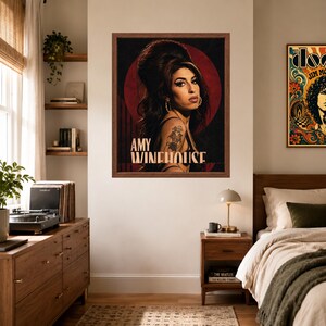 Puede incluir: Una l&aacute;mina enmarcada con un retrato de Amy Winehouse con su caracter&iacute;stico peinado de colmena, delineador de ojos oscuro y un tatuaje visible en el brazo. El fondo es un c&iacute;rculo rojo intenso sobre un fondo negro, con el texto AMY WINEHOUSE debajo.