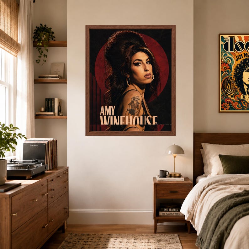 Puede incluir: Una l&aacute;mina enmarcada con un retrato de Amy Winehouse con su caracter&iacute;stico peinado de colmena, delineador de ojos oscuro y un tatuaje visible en el brazo. El fondo es un c&iacute;rculo rojo intenso sobre un fondo negro, con el texto AMY WINEHOUSE debajo.