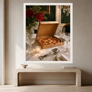 May include: A cardboard pizza box containing a round pizza with red sauce and toppings sits on a white tablecloth. Nearby are two crystal glasses, a small lit candle in a glass holder, silver serving tongs, and a vase of red flowers.