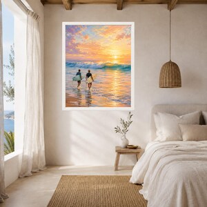 May include: A framed wall art print featuring a sunset ocean scene with two individuals carrying surfboards into the water. The sky is filled with vibrant orange, yellow, and pink clouds above a breaking wave, reflecting light onto the wet sand.