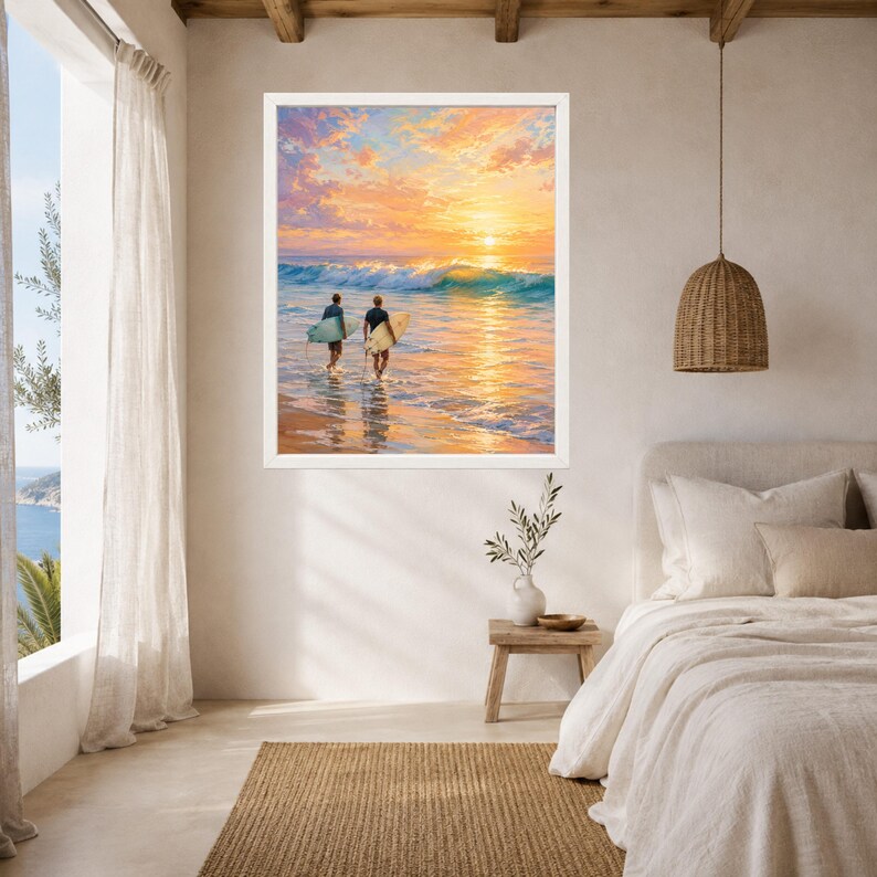 May include: A framed wall art print featuring a sunset ocean scene with two individuals carrying surfboards into the water. The sky is filled with vibrant orange, yellow, and pink clouds above a breaking wave, reflecting light onto the wet sand.