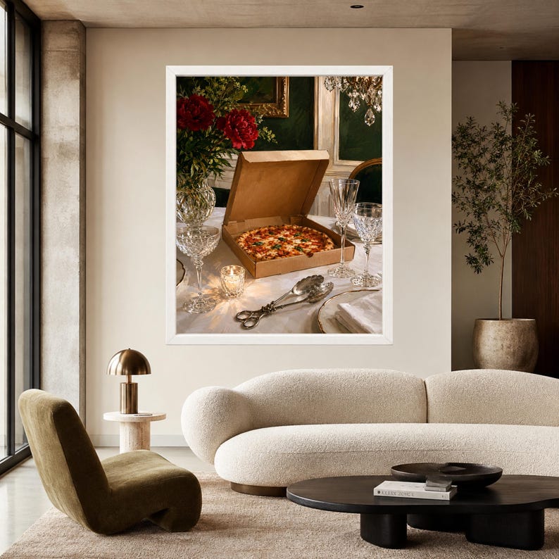 May include: A framed wall art print featuring a cardboard pizza box open on a white tablecloth, revealing a round pizza. The scene includes two crystal wine glasses, a small lit candle, a vase with red flowers, and silver serving tongs.