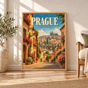 Framed Prague Czechia travel poster showing a flower-lined cobblestone street descending toward the Vltava River, Charles Bridge and Prague Castle beneath a bright blue sky.