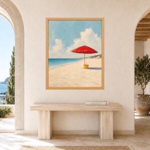 May include: A framed wall art print depicting a sunny beach scene with a bright red beach umbrella and a yellow tote bag resting on the sand. The painting features a clear blue sky with white clouds, a calm ocean, and a sandy shoreline in a light wood frame.