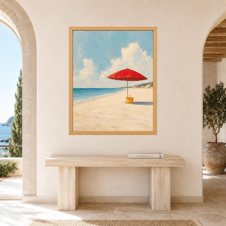 May include: A framed wall art print depicting a sunny beach scene with a bright red beach umbrella and a yellow tote bag resting on the sand. The painting features a clear blue sky with white clouds, a calm ocean, and a sandy shoreline in a light wood frame.