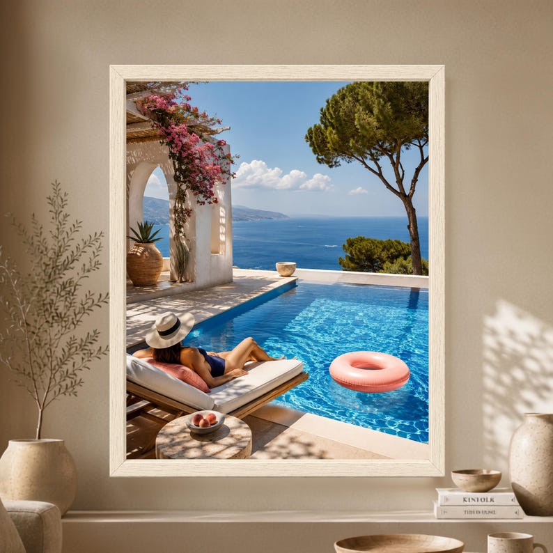 Framed Mediterranean poolside wall art showing a woman relaxing on a lounger beside a bright blue infinity pool overlooking the sea with bougainvillea, white arches and a pink pool float.