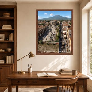 K&ouml;nnte beinhalten: Ein gerahmter Wandkunstdruck, der eine Luftaufnahme der antiken Stadt Pompeji mit dem Vesuv im Hintergrund zeigt. Das Bild zeigt Steingeb&auml;ude, einen zentralen Platz und den Text POMPEII 79 CE in wei&szlig;er Schrift unten in der Mitte.