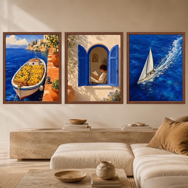 May include: A set of three framed wall art prints featuring Mediterranean scenes. The left print shows a boat filled with lemons docked by a stone wall. The center print depicts an open blue window with a person reading. The right print shows a sailboat.