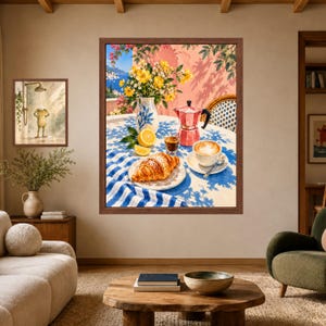 May include: A framed wall art print depicting a breakfast scene on a balcony with a croissant, a cup of coffee, a moka pot, a vase of yellow flowers, and lemon slices on a blue and white striped tablecloth, with a coastal view in the background.